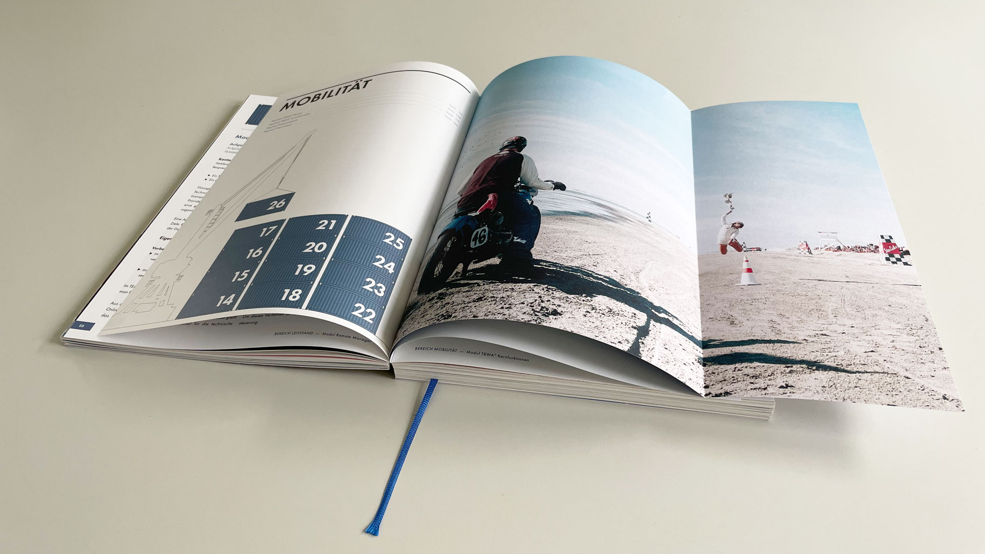 Katalog-magrathea-aufgeschlagen Aufgeschlagener Katalog. Eine SEite zeigt eine Grafik mit Schiffscontainern, die andere Seite eine Strandscene